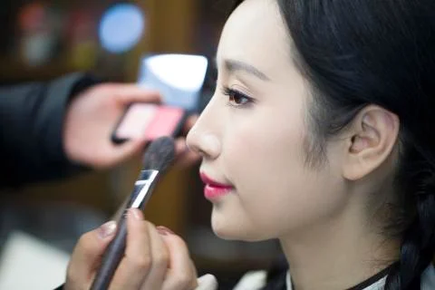 Makeup artist applying make-up to young woman Stock Photos