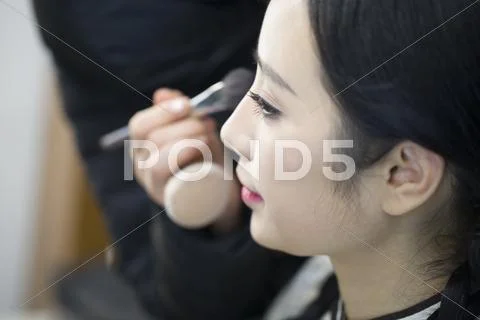 Makeup artist applying make-up to young woman Stock Photos