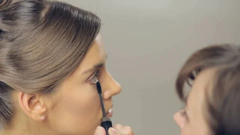 Makeup artist applying makeup on bottom eyelashes. Panning Stock Footage 72143345