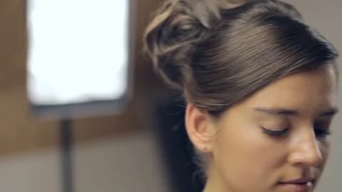 Makeup artist applying makeup with a brush on cheek of young woman. Panning Stock Footage 72129719