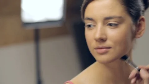 Makeup artist applying makeup with a brush on neck of young woman. Panning Stock Footage 72129859