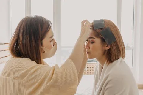Makeup artist is applying makeup on client eyes. Stock Photos