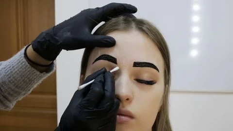 Makeup artist applying makeup to the eyebrows of the model. Close-up view Stock Footage 83710179
