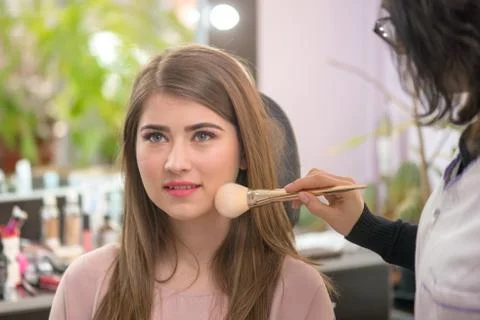 Makeup artist applying makeup to model in salon. Stock Photos