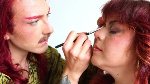 Makeup artist applying makeup on a red-haired woman Stock Footage 309130283