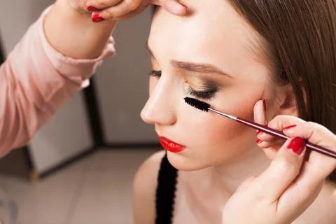 Makeup artist applying mascara on a model close up Stock Photos