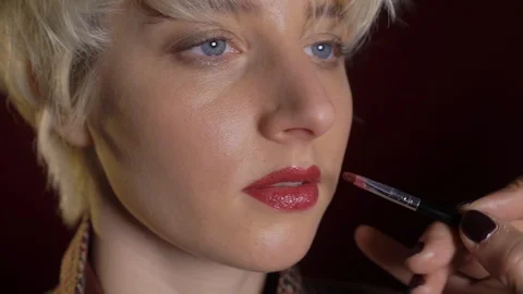 Makeup artist applying red lipstick on model lips with brush in studio Stock Footage 123634274