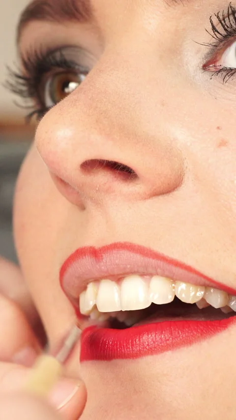 Makeup artist applying red lipstick to female lips. Vertical video Stock Footage 336428807