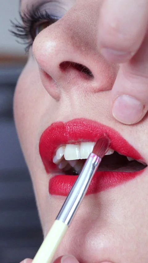 Makeup artist applying red lipstick to female lips. Vertical video Stock Footage 336428994