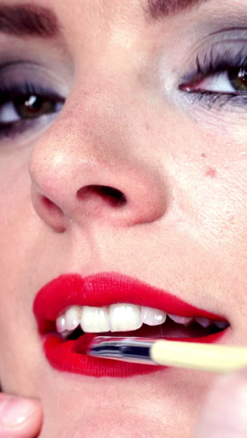 Makeup artist applying red lipstick to female lips. Vertical video Stock Footage 336429178