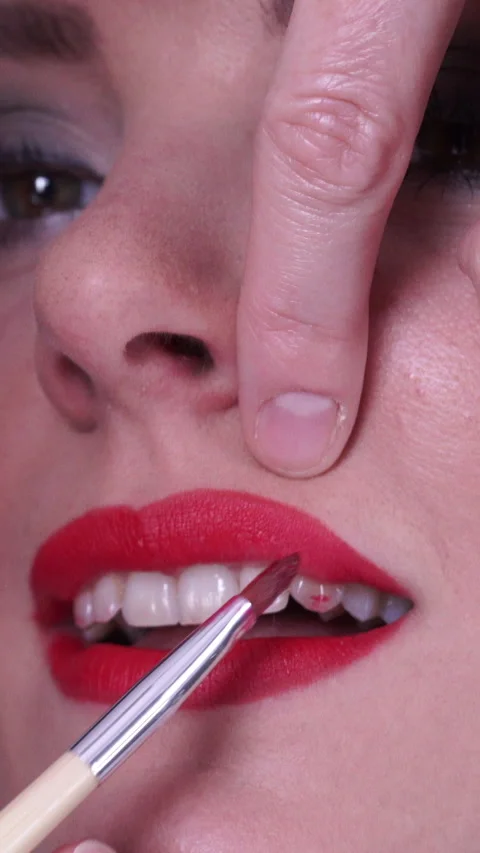 Makeup artist applying red lipstick to female lips. Vertical video Stock Footage 336429213