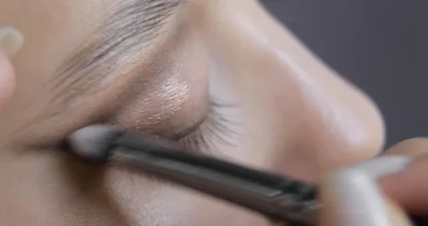 Makeup artist applying shiny eye shadows to eyelid of young woman, eye closeup. Stock Footage 145503491