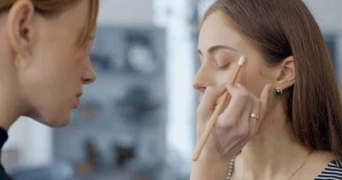Makeup artist blending eyeshadows to model in beauty salon Stock Footage 126182904