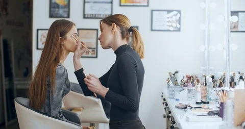 Makeup artist blending eyeshadows to model in beauty salon Stock Footage 126182912
