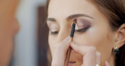 Makeup artist blending eyeshadows to model in beauty salon Stock Footage 126183764