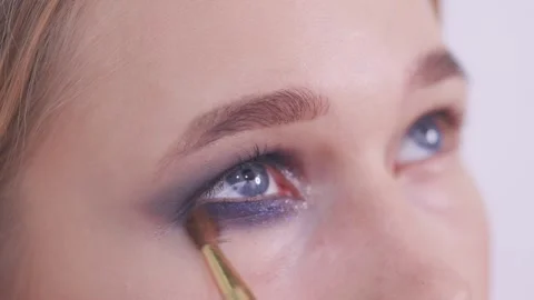 Makeup artist blends blue glitter eyeshadow under eye. Stock Footage 142135492