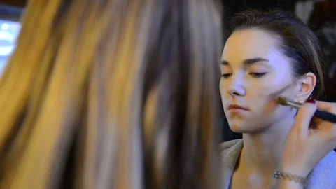 Makeup artist Blush dark blushes on brown long-haired model in studio Stock Footage 78630901