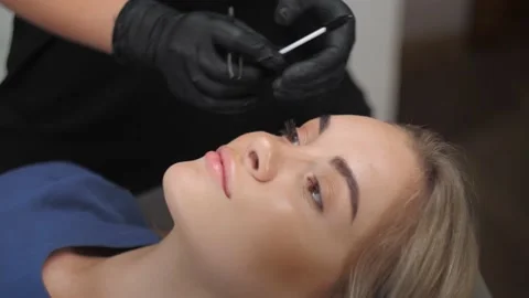 A makeup artist brushes the eyebrows of a young girl with healthy face skin  Stock Footage 198881030
