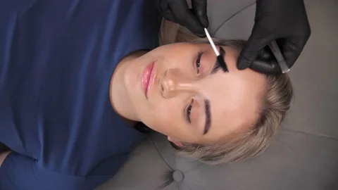 A makeup artist brushes the eyebrows of a young girl with healthy face skin  Stock Footage 198881114