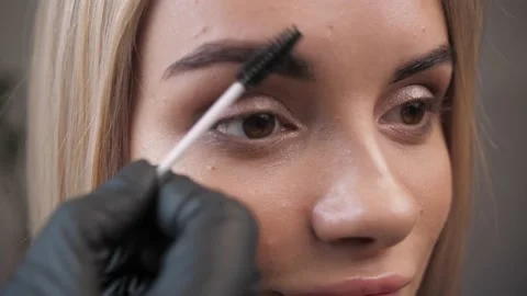 Makeup artist brushes the eyebrows of a young girl with healthy face skin  Stock Footage 198881454