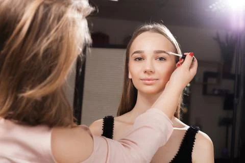 Makeup artist brushing eyebrows of a client Stock Photos