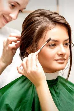 Makeup artist combing eyebrows and hairstylist preparing hairstyle Stock Photos