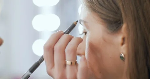 Makeup artist combs and draws a model eyebrows with pencil Stock Footage 126181425