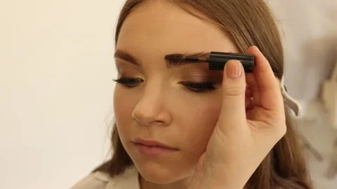 Makeup artist combs eyebrow models with a brush, make up process in slow motion Video stock 162348317