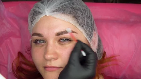 Makeup artist combs eyebrows after dyeing in a beauty salon. Stock Footage 231251656