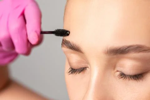 Makeup artist combs eyebrows with a brush after dyeing in a beauty salon.Prof Stock Photos