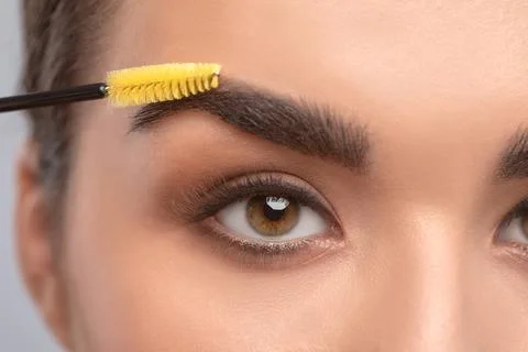 Makeup artist combs eyebrows with a brush after dyeing in a beauty salon.Prof Foto stock