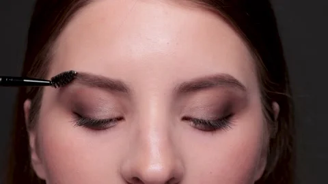 Makeup artist combs eyebrows before coloring in a beauty salon. Stock Footage 203965265