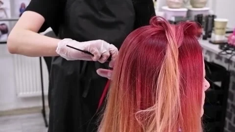 Makeup artist combs a strand of pink hair with a hairdressing tool Stock Footage 165450932
