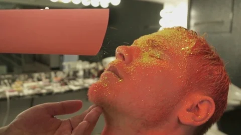 Makeup artist covering colored man with the sparkles, slow motion Stock Footage