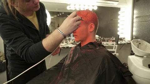 Makeup artist covering model's face with bright orange color Stock Footage 73538501