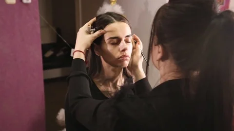 Makeup artist creates the shape of the eyebrows for the model Stock Footage 84988901