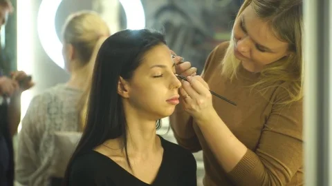 Makeup artist creating beautiful makeup for brunettemodel Stock Footage 76247514