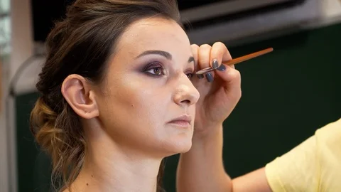 A makeup artist draws a beautiful model's eye with a bright shining eye shadows 動画素材 127501467