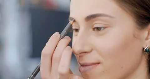 Makeup artist draws a model eyebrows with pencil Stock Footage 126181698