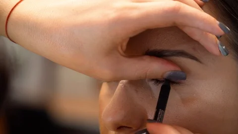 A makeup artist draws model's contour of the eye with a black pencil 動画素材 127501806