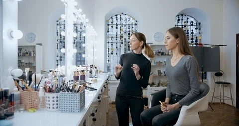 Makeup artist evaluates to model in mirror in beauty salon Stock Footage 126184279