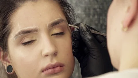 Makeup artist fixing the shape of eyebrows for a woman Video stock 73673701