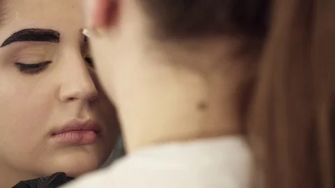 Makeup artist fixing the shape of painted eyebrows closeup Video stock 73676339