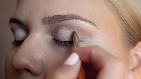 Makeup artist hand paints upper eyelid with gray shadows. Stock Footage 103302066
