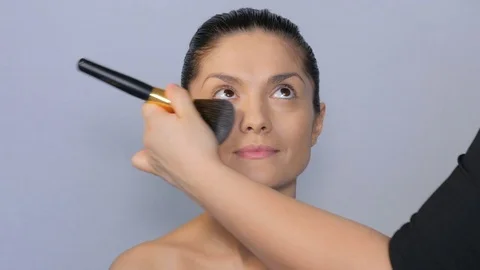 Makeup artist makes a beautiful makeup to a girl. Face of a beautiful girl close Video stock 77326570