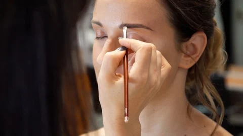 A makeup artist makes a contour of the eyebrows with a brush 스톡 동영상 127501217