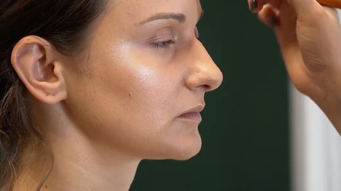 A makeup artist makes a contour of the face of a model with a makeup brush 스톡 동영상 127501338