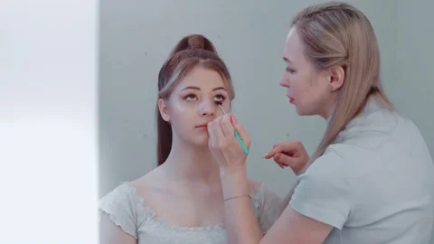 Makeup artist makes eyelash makeup with a brush for a beautiful girl Stock Footage 149687030