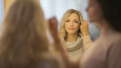 Makeup artist makes makeup beautiful girl Stock Footage