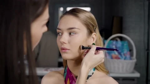 The makeup artist makes a makeup of the model. Sculptor applies to the cheek Stock Footage 235618529